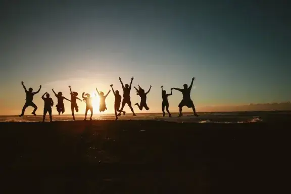 A group of happy travelers on a tropical Maldives beach during sunset – About Cheap Maldives